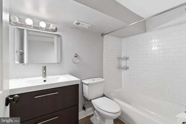 a view of a hallway with wooden floor and a bathroom