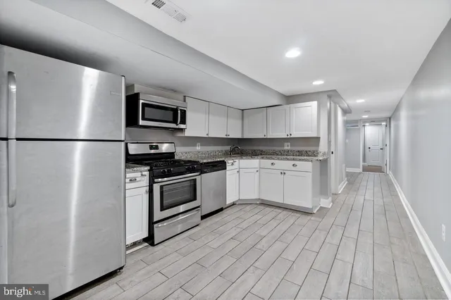 a kitchen with white cabinets stainless steel appliances and wooden floor