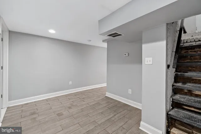 a view of an empty room with wooden floor and stairs