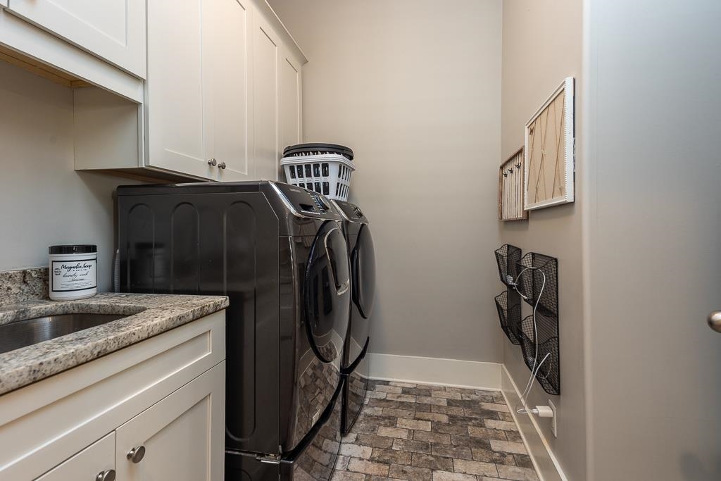 328 Washington Street Collierville, TN 38017 - Photo 21 of 33 Utility room featuring a built-in sink with a granite-style countertop, white cabinetry with silver-tone hardware, and a stone-look floor