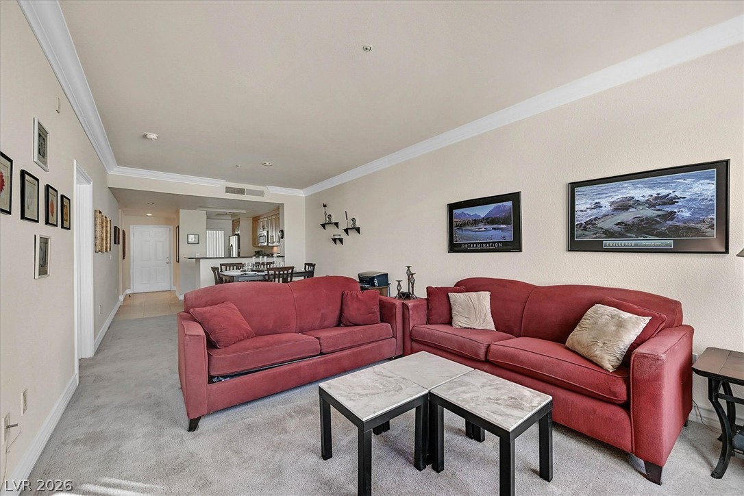 220 East Flamingo Road, Unit 305 Las Vegas, NV 89169 - Photo 5 of 26 Well-lit living room offers comfortable carpet flooring and a clear view to the dining area and kitchen.
