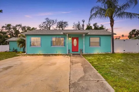 a view of a house with a yard and palm trees