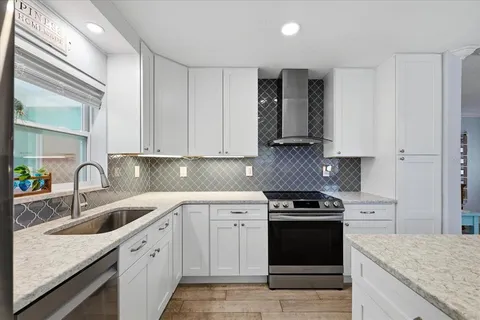 a kitchen with granite countertop white cabinets and stainless steel appliances