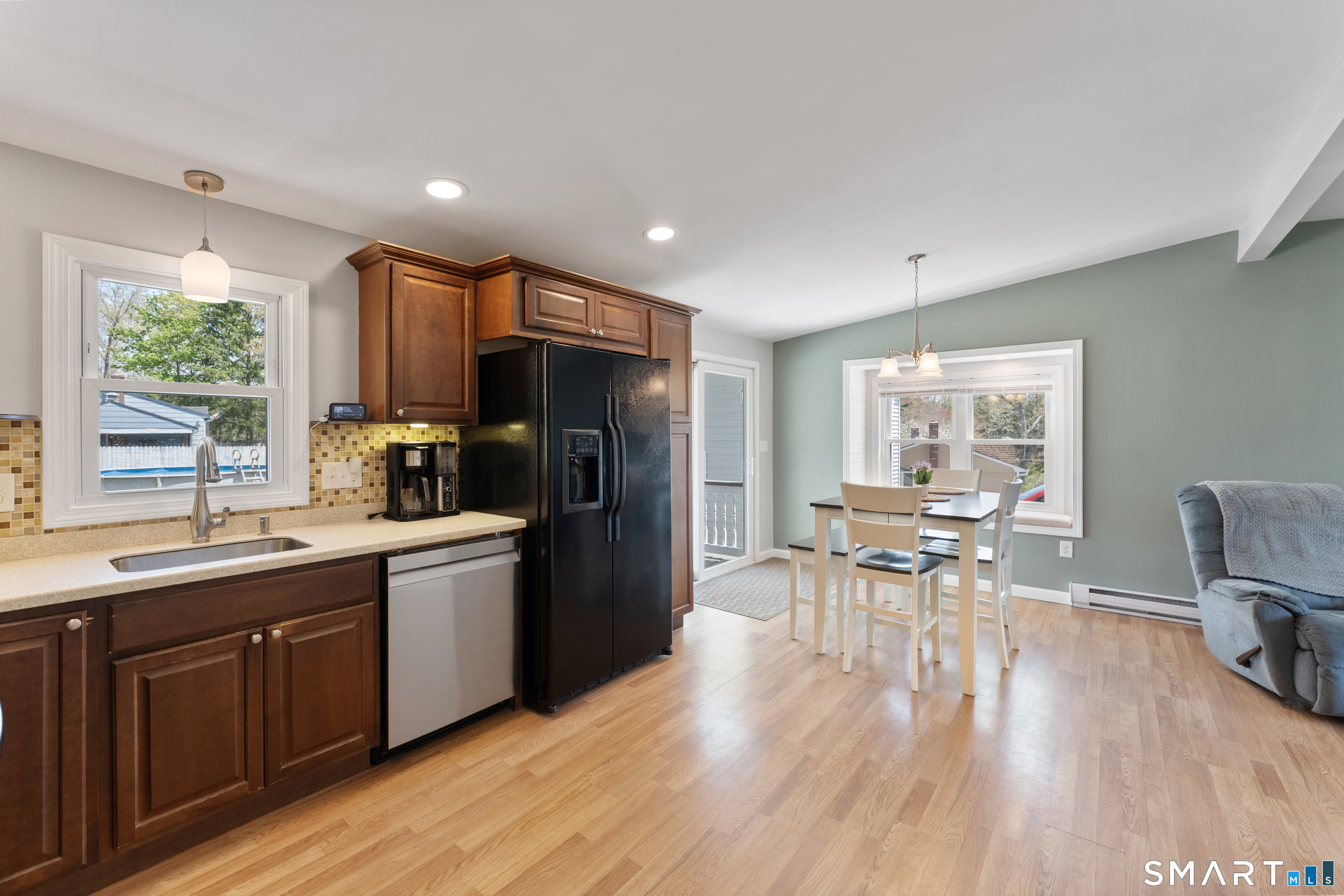 56 Thompson Hill Road Thompson, CT 06255 - Photo 12 of 38 a kitchen with stainless steel appliances granite countertop a refrigerator a sink dishwasher a dining table and chairs with wooden floor