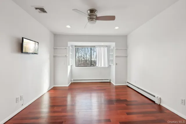 an empty room with wooden floor chandelier fan and windows