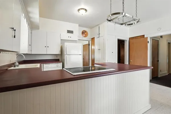 a kitchen with stainless steel appliances granite countertop a refrigerator a stove and a sink with chandelier