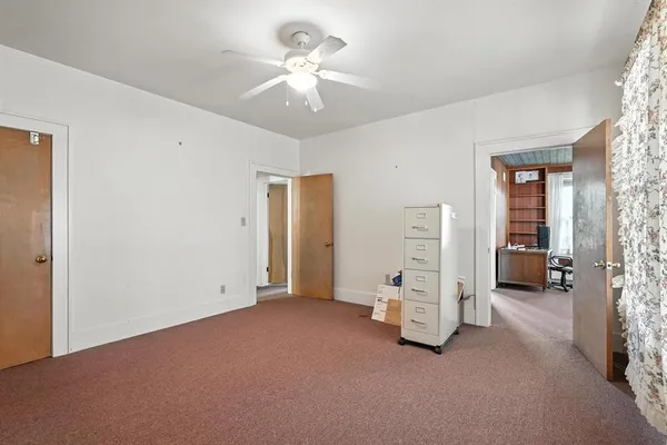 an empty room with a chandelier fan and closet area