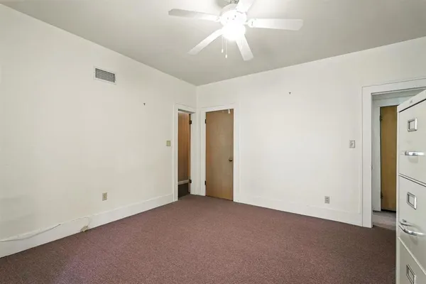 a view of an empty room with window and chandelier fan