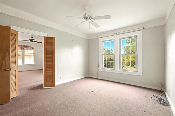 an empty room with closet and a ceiling fan