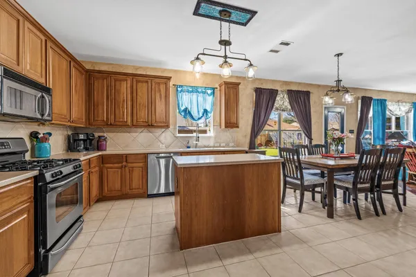 a kitchen with kitchen island granite countertop a stove a sink a dining table and chairs