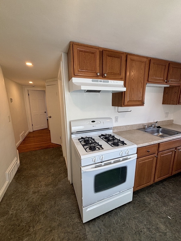 79 Pleasant Street, Unit 1 Stoneham, MA 02180 - Photo 3 of 7 a kitchen with granite countertop a stove and a sink