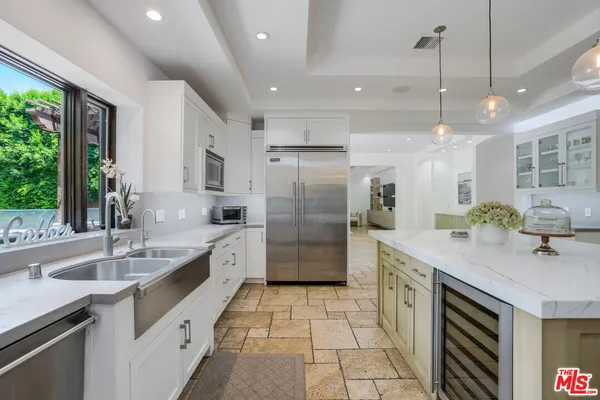 a large kitchen with a large counter top a sink stainless steel appliances and windows