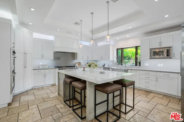 a kitchen with kitchen island granite countertop a sink a center island stainless steel appliances and cabinets