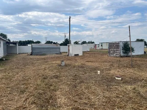 a view of a dry yard with wooden fence