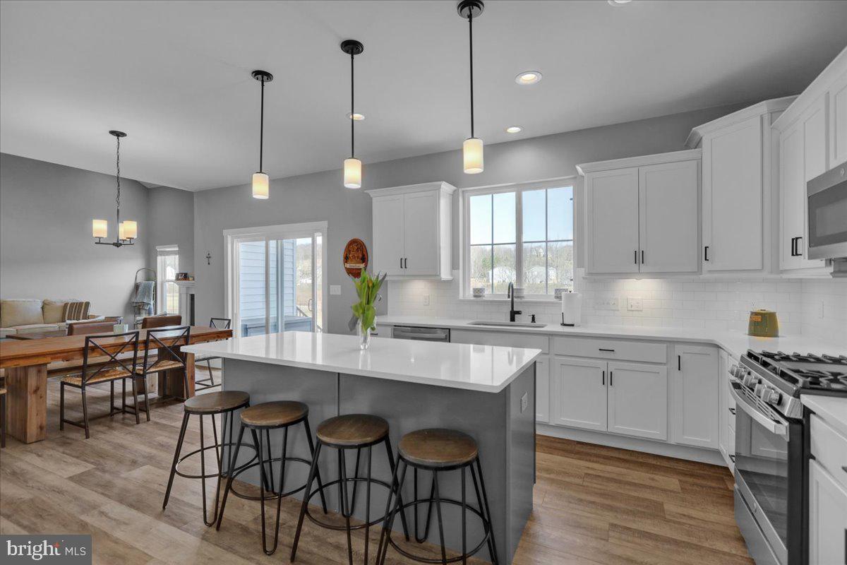 1057 Ryebrook Road Reading, PA 19608 - Photo 13 of 49 a large kitchen with kitchen island a dining table chairs and a wooden floor