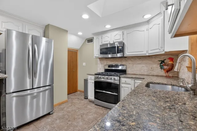 a kitchen with stainless steel appliances granite countertop a refrigerator sink and stove
