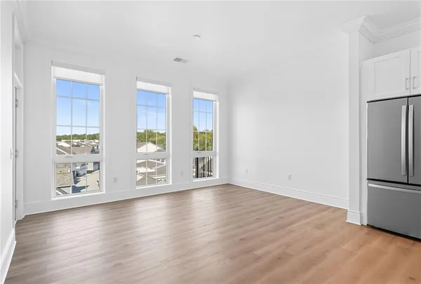 an empty room with wooden floor and windows