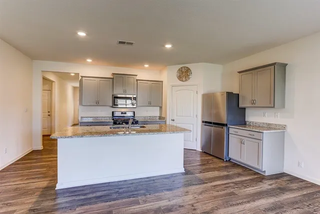 a kitchen with stainless steel appliances granite countertop a refrigerator a stove top oven a sink and dishwasher