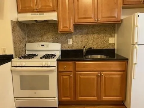 a kitchen with granite countertop cabinets appliances and a counter space