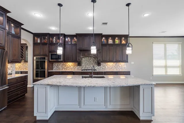 a kitchen with stainless steel appliances granite countertop a sink a refrigerator and a wooden floor