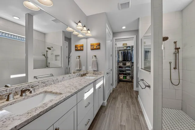 a spacious bathroom with a granite countertop sink a mirror a shower and a bathtub