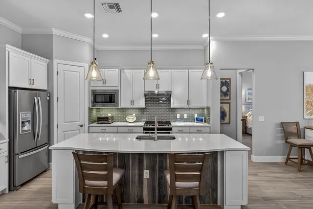 a kitchen with stainless steel appliances granite countertop a table chairs stove and refrigerator