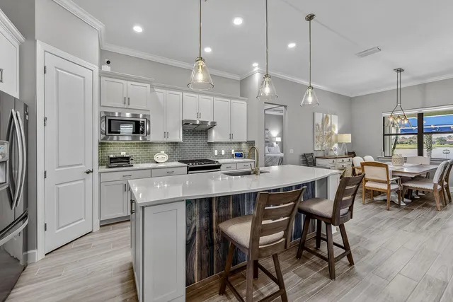 a kitchen with stainless steel appliances granite countertop a stove a refrigerator a kitchen island a sink cabinets and a refrigerator