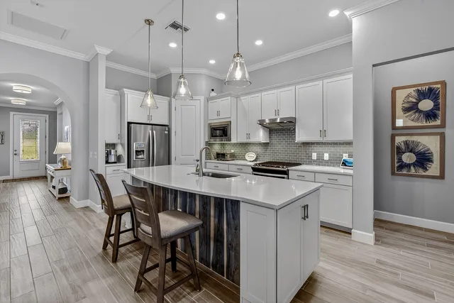 a kitchen with stainless steel appliances kitchen island granite countertop a table chairs refrigerator and microwave