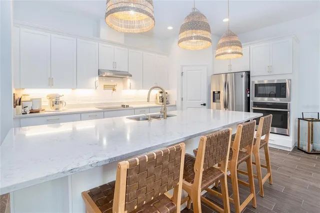 a kitchen with stainless steel appliances granite countertop a sink a oven a dining table and chairs with wooden floor