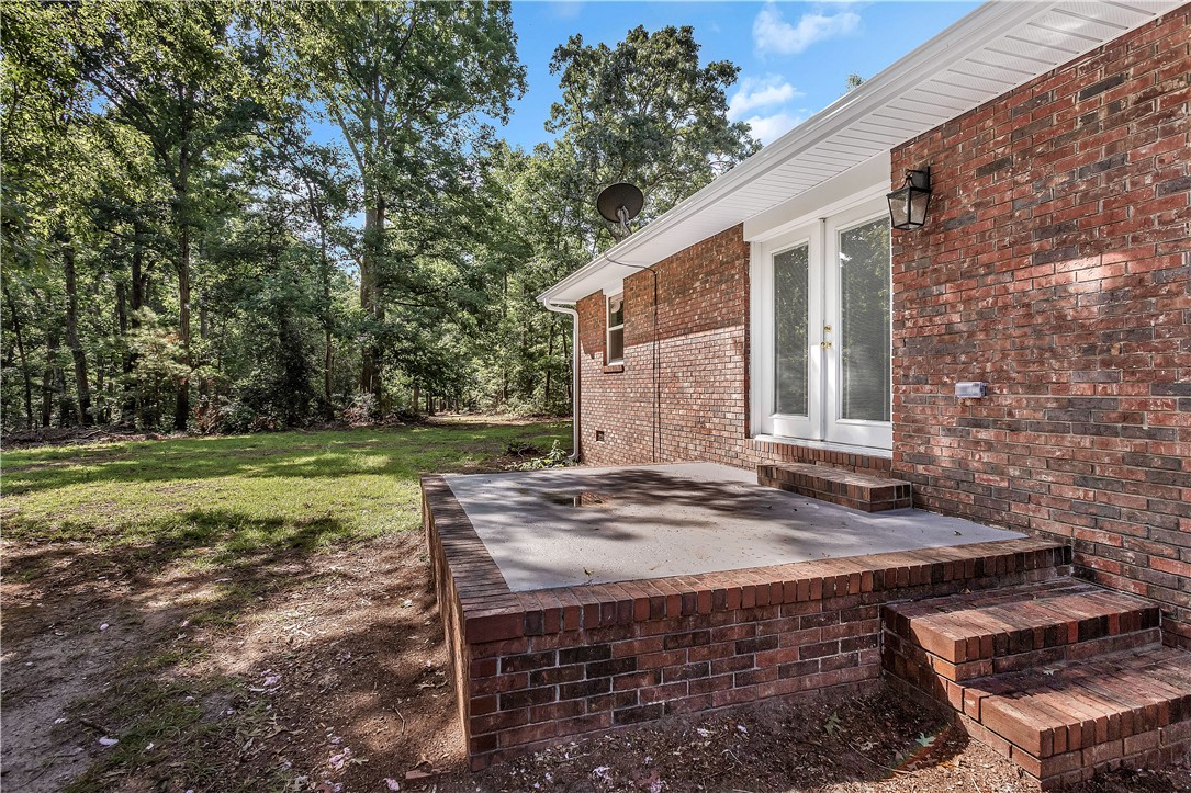 809 Paige Road Honea Path, SC 29654 - Photo 28 of 33 Brick exterior with white trim, featuring a raised patio with brick stairs and a pair of double glass doors