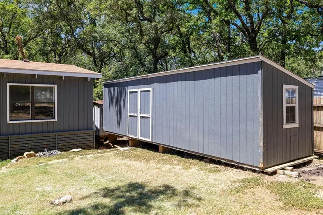 a backyard of a house with large trees and wooden fence