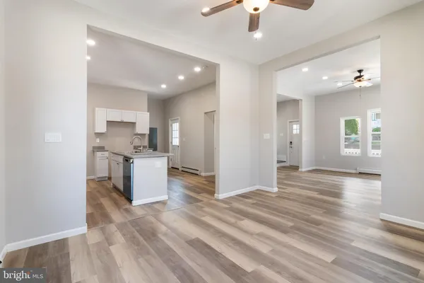 a view of kitchen and empty room with wooden floor