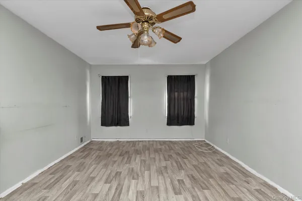 a view of an empty room with window and wooden floor