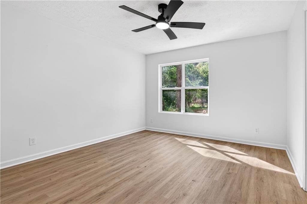 170 Kipling Way Riverdale, GA 30274 - Photo 8 of 16 an empty room with wooden floor ceiling fan and windows