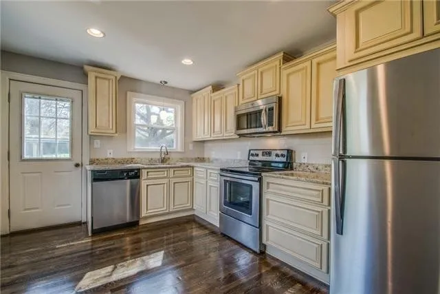a kitchen with granite countertop a refrigerator stove and microwave