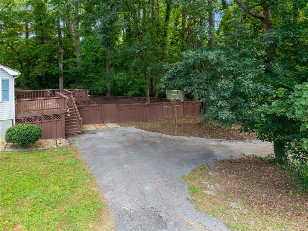 98 Blue Ridge Drive Clemson, SC 29631 - Photo 26 of 32 A spacious driveway and private wooden deck adjoin a fenced yard bordered by mature trees.