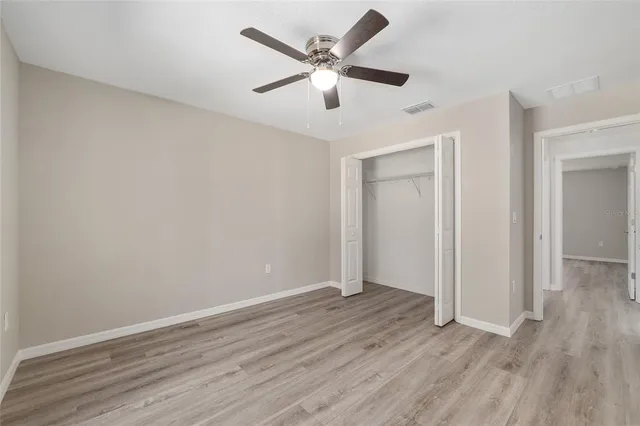 an empty room with wooden floor and ceiling fan