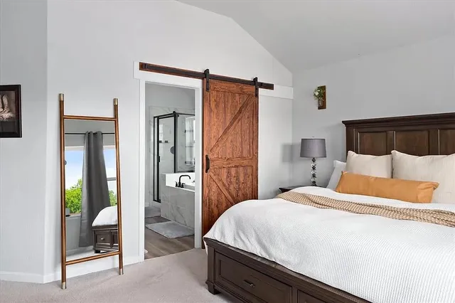 a bedroom with a bed painting on wall and a large window