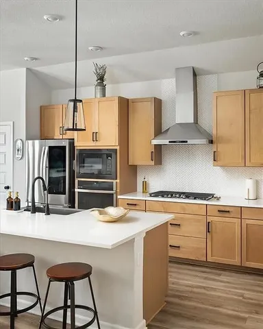 a kitchen with stainless steel appliances kitchen island a table chairs in it and wooden floors