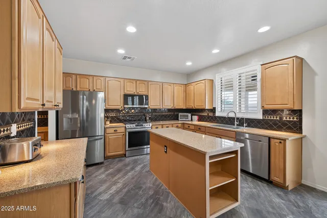 a kitchen with a chandelier stainless steel appliances cabinets and a counter top space