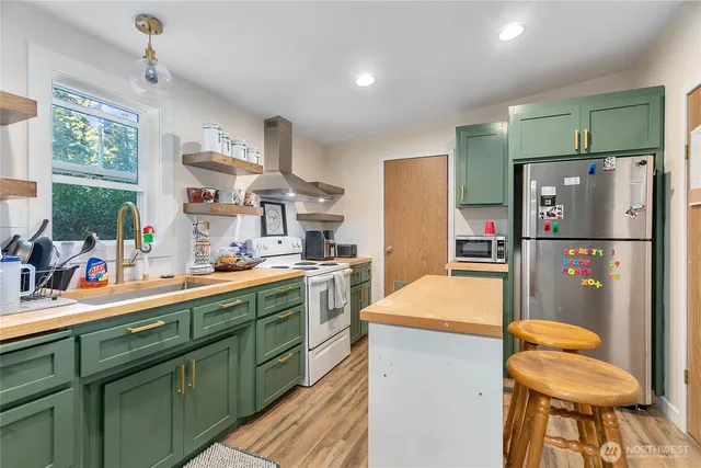 a kitchen with stainless steel appliances kitchen island granite countertop refrigerator sink and cabinets