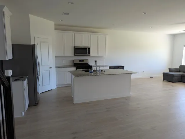 a kitchen with stainless steel appliances a stove a refrigerator a sink a stove with white cabinets