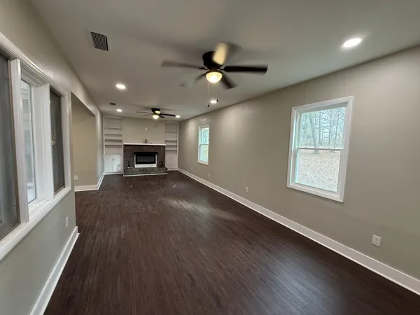 a view of an empty room with a window and a kitchen