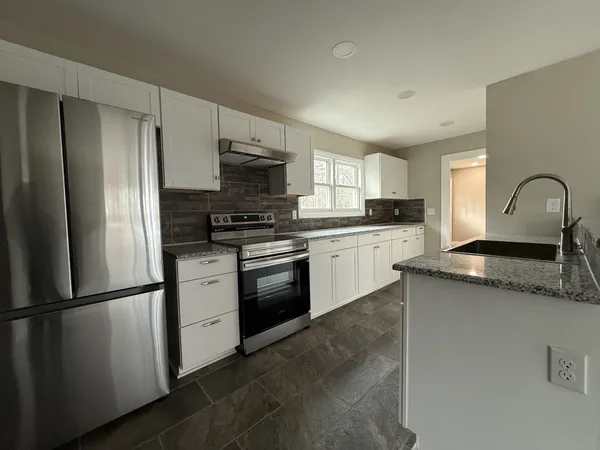 a kitchen with stainless steel appliances granite countertop a refrigerator sink and stove