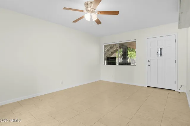 an empty room with windows and fan