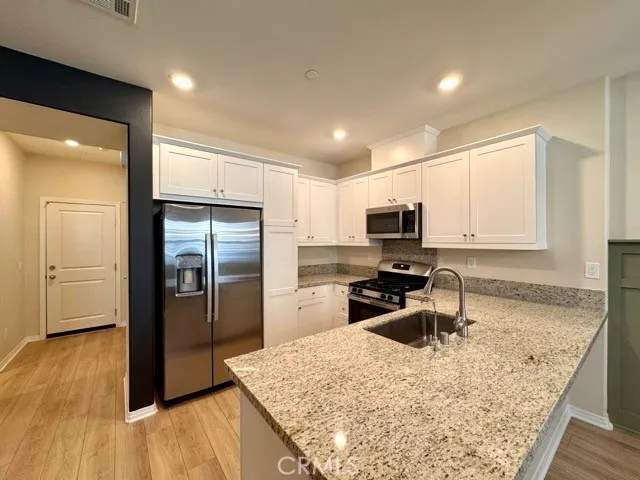 a large kitchen with a stove top oven a sink and stainless steel appliances
