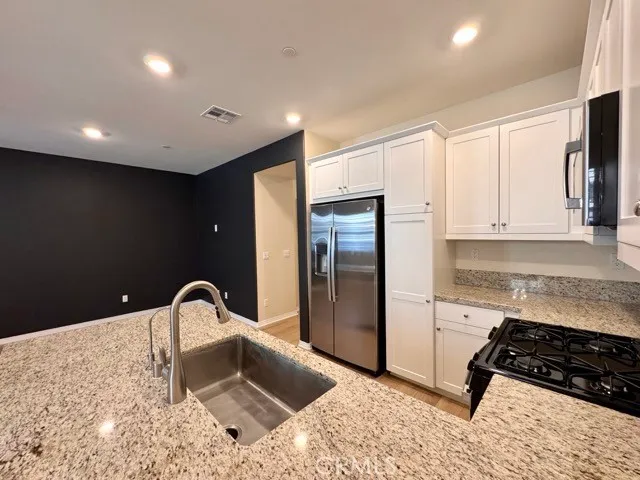 a kitchen with stainless steel appliances granite countertop a refrigerator and a stove top oven
