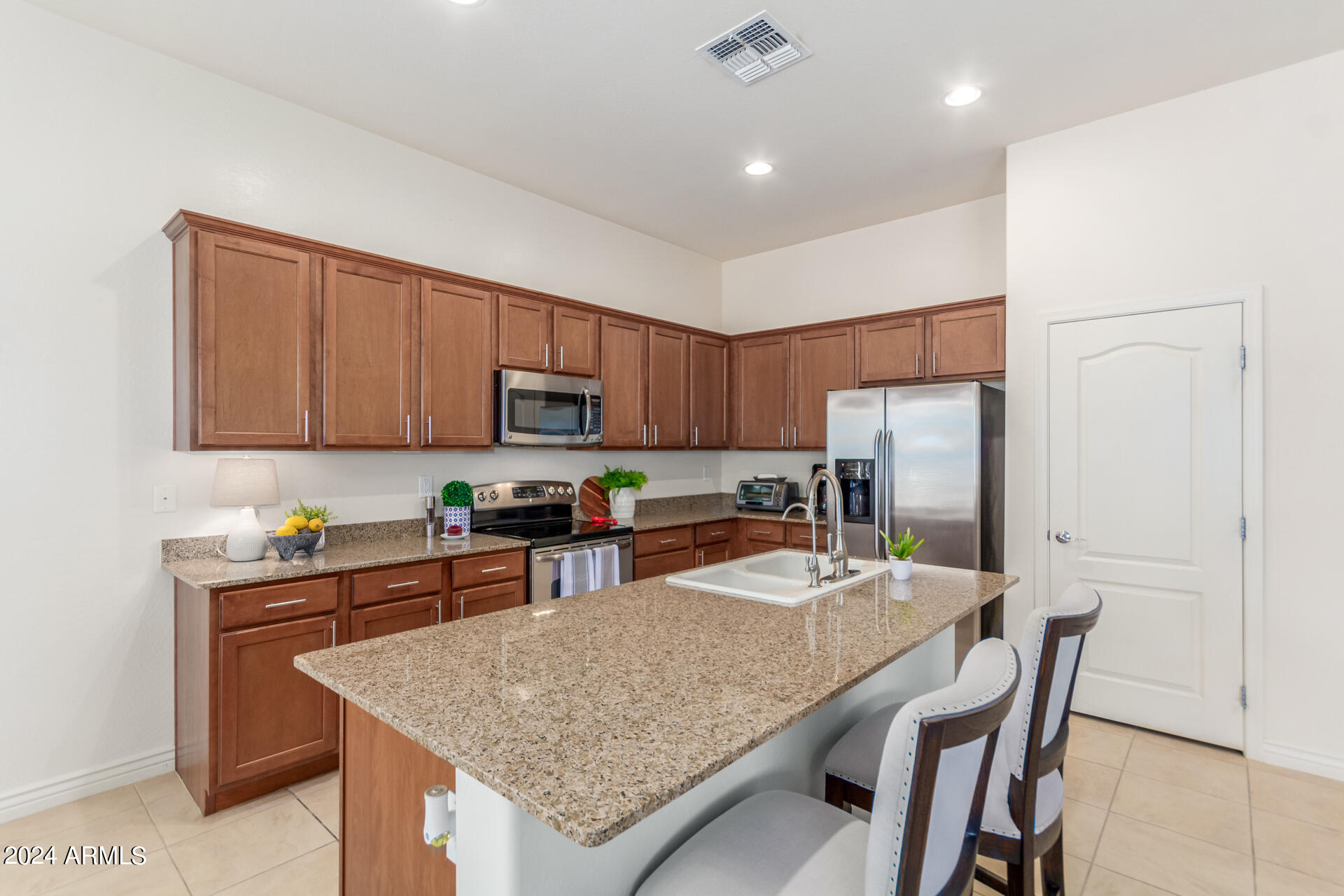 17858 West Verdin Road Goodyear, AZ 85338 - Photo 14 of 78 a kitchen with stainless steel appliances granite countertop a table chairs sink refrigerator and microwave
