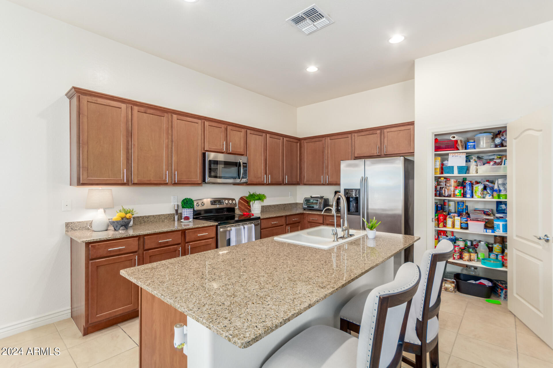 17858 West Verdin Road Goodyear, AZ 85338 - Photo 15 of 78 a kitchen with stainless steel appliances granite countertop a table chairs sink refrigerator and stove
