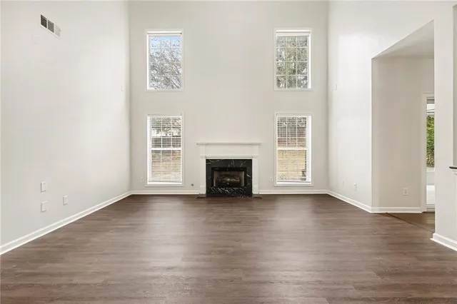 a view of an empty room with wooden floor fireplace and a window